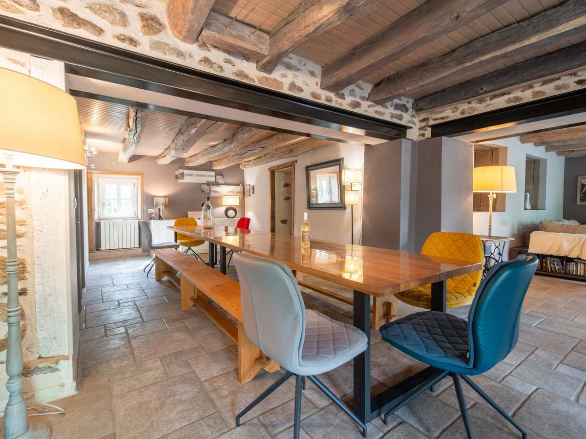 Grande salle à manger sous poutres apparentes, dressée pour vingt convives