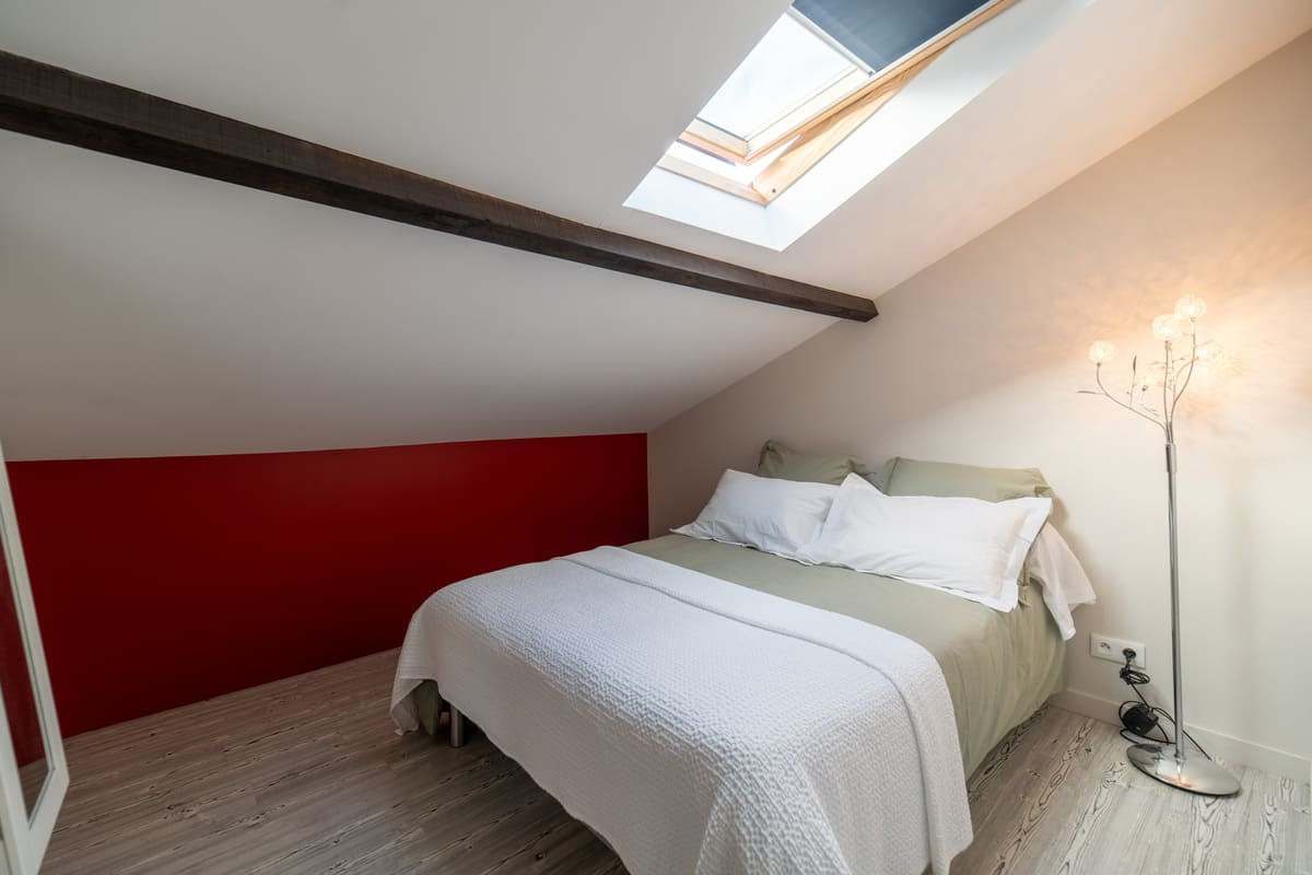 Chambre sous combles avec velux et tête de lit rouge