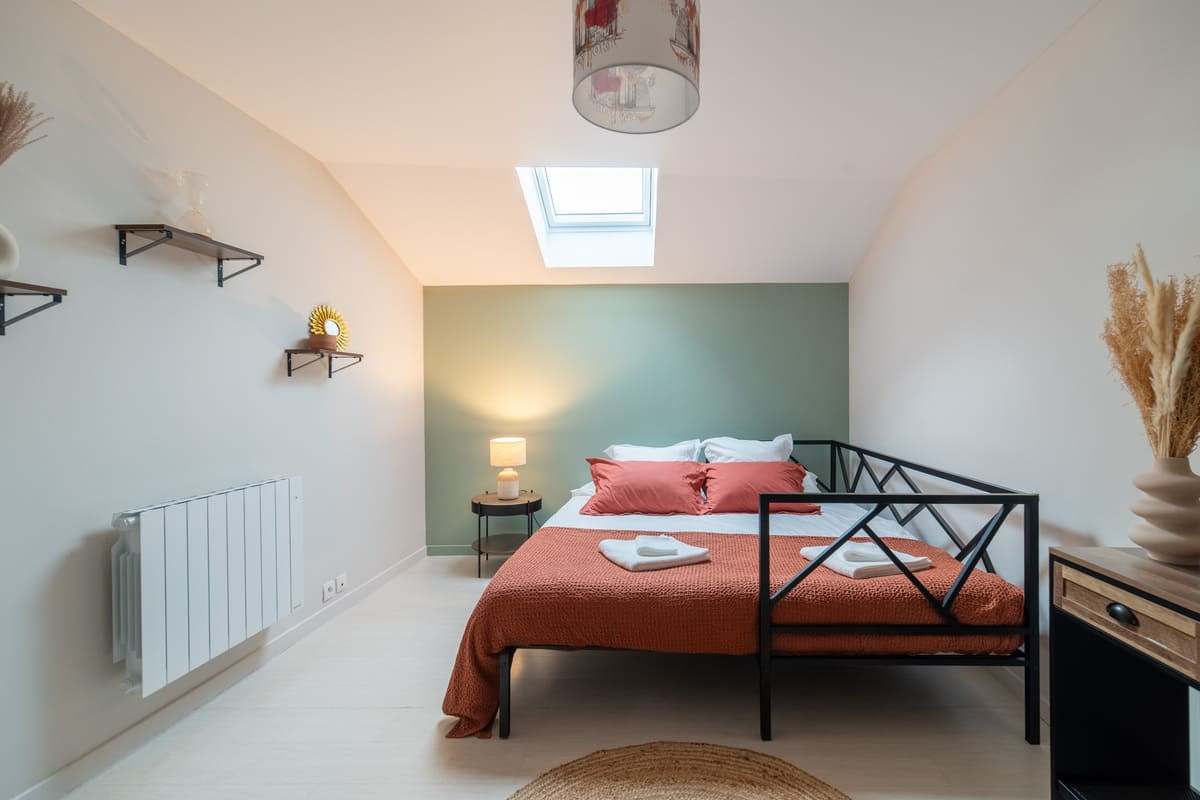 Chambre mansardée au lit en métal noir et mur vert d’eau