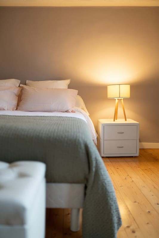 Chambre aux tons poudrés avec chevet et lampe d’appoint