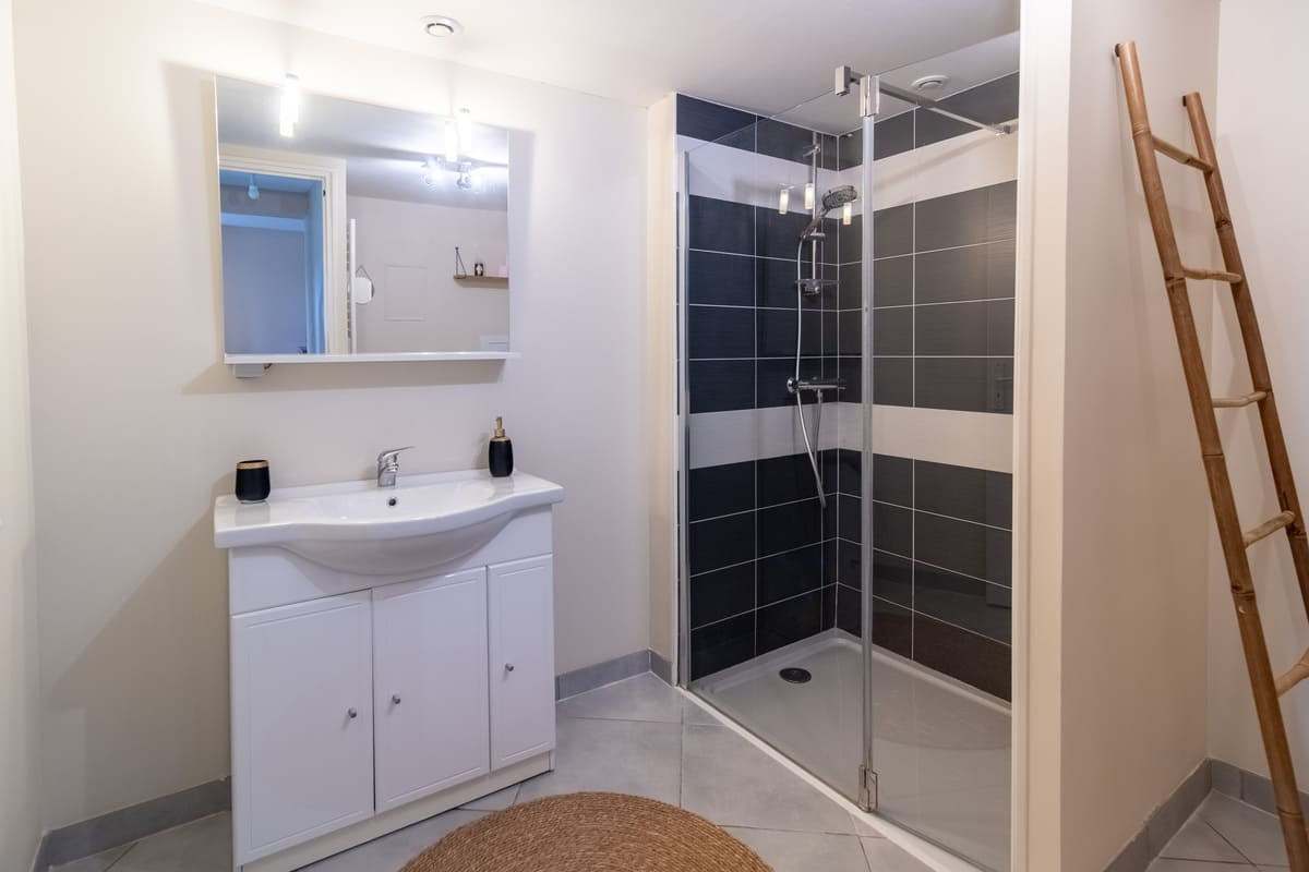 Salle d’eau avec douche carrelée noire et vasque blanche