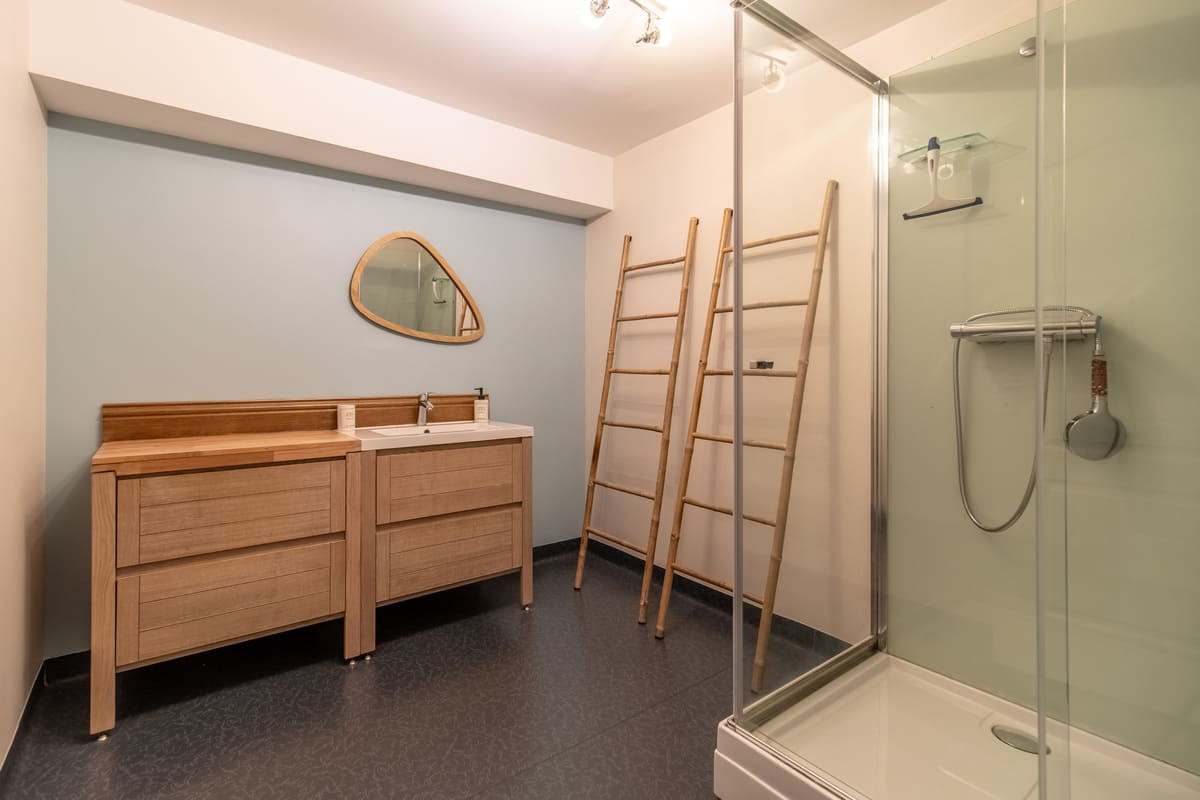 Salle d’eau avec commode en bois et douche vitrée