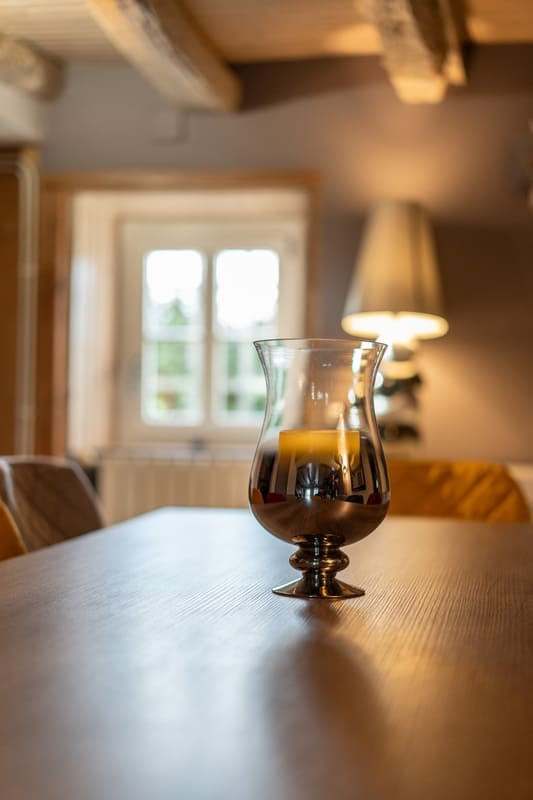 Détail d’un verre posé sur la grande table en bois